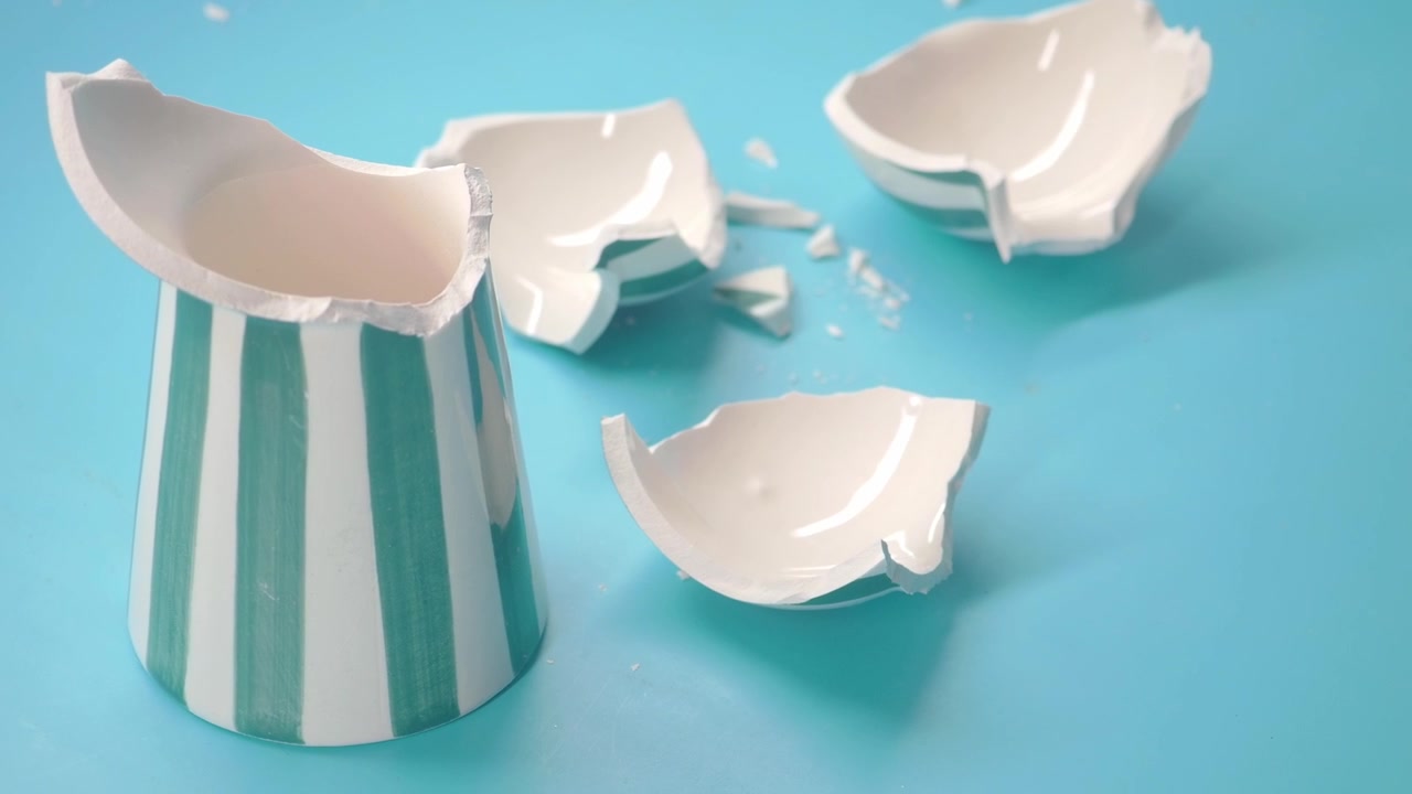 Broken Ceramic Cup With Green Stripes on Blue Background