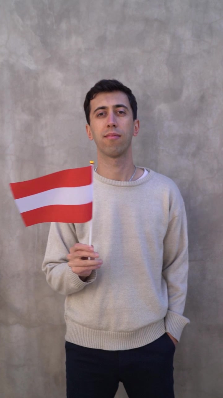 Rekaman vertikal seorang pria mengibarkan bendera Austria. Konsep patriotisme. Gerak lambat
