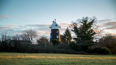 windmill house at sunrise with fast clouds above