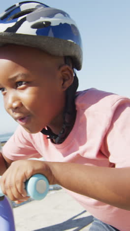 video of happy african american boy riding scooter by sea