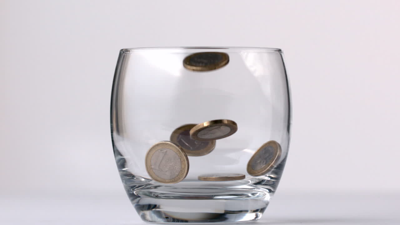 Monete di euro che cadono in un bicchiere