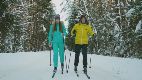 un hombre con una chaqueta amarilla y una mujer con un mono azul en el invierno en el bosque esquiando en cámara lenta