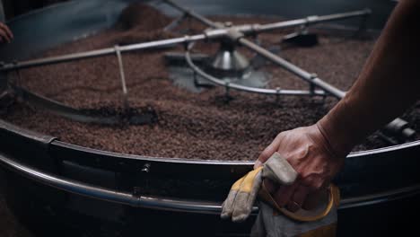 coffee roasting process - man waits beside large coffee roasting machine.