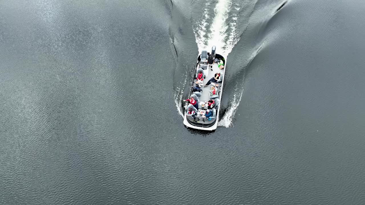 Birds eye view of a pontoon boat in slow motion, with people enjoying food and tossing shrimp shell