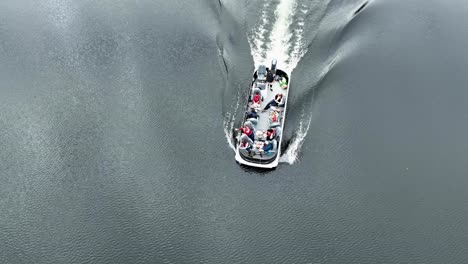 birds eye view of a pontoon boat in slow motion, with people enjoying food and tossing shrimp shell