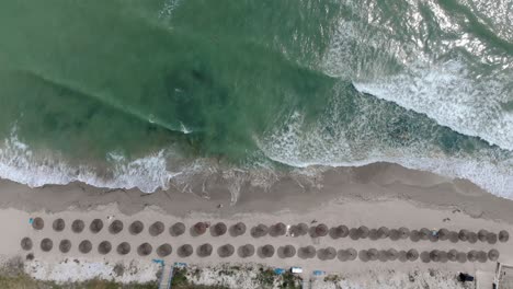 Vista-Panorámica-De-La-Playa-Con-Sombrillas-Y-Orilla-Arenosa-En-Vama-Veche,-Rumania---Tiro-Con-Drones