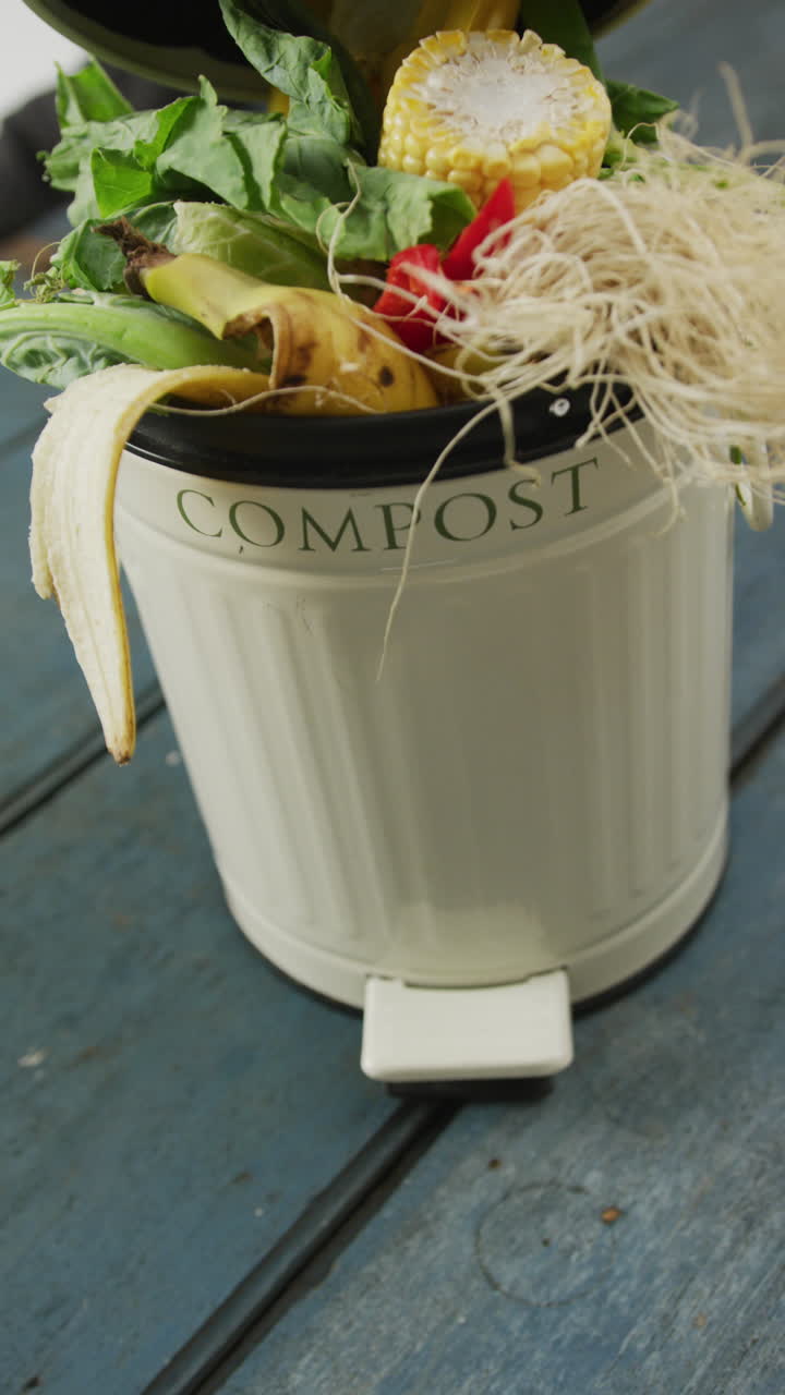 vídeo vertical de un contenedor de compost con residuos orgánicos sobre un fondo de madera gris