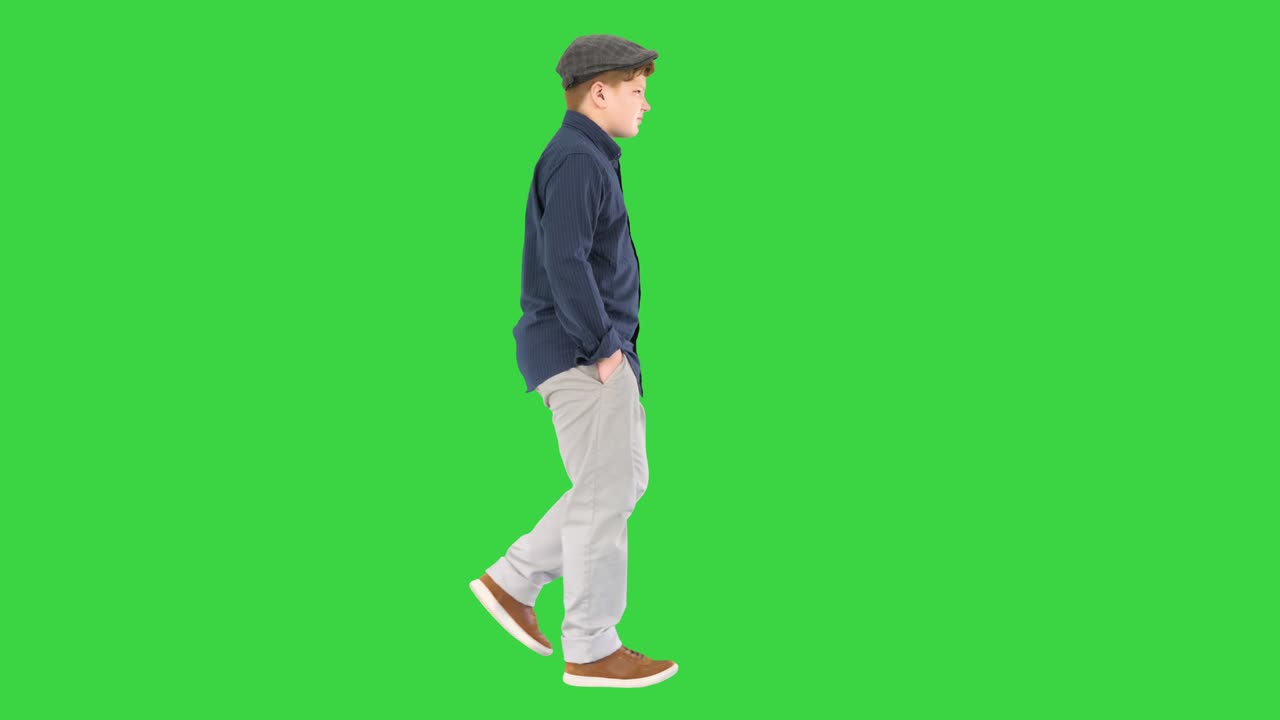 Stylish teenage boy in a shirt and a cap walking on a Green Screen, Chroma Key