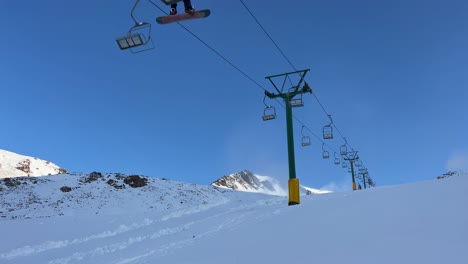 two-seater chair lift on a quiet day at a ski field underneath blue skies