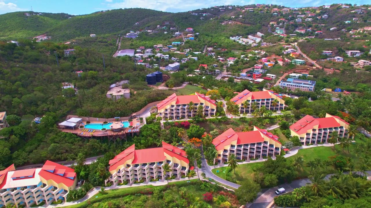 Luftaufnahme mit Neigung nach oben und Rückzug von einem Hotel in St. Thomas, USVI, üppiges Grün und lebendige Berglandschaft mit Häusern am Hang
