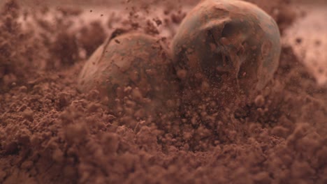 chocolate truffles falling into chocolate powder in super slow motion.