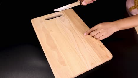 hands cleaning and inspecting a wooden cutting board