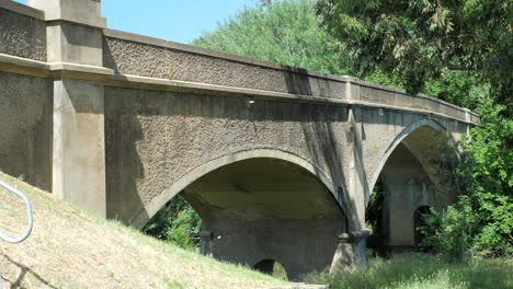 old historic cement arch bridge over moorabool river, pan right