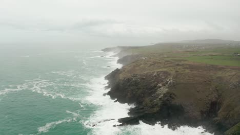 aerial rotation from the rocky shores of cornwall toward the misty atlantic ocean horizon