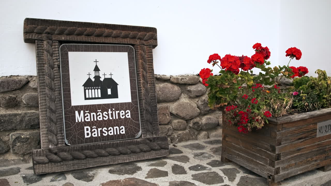 View of the Barsana Monastery sign on the ground, flowers near it, Romania