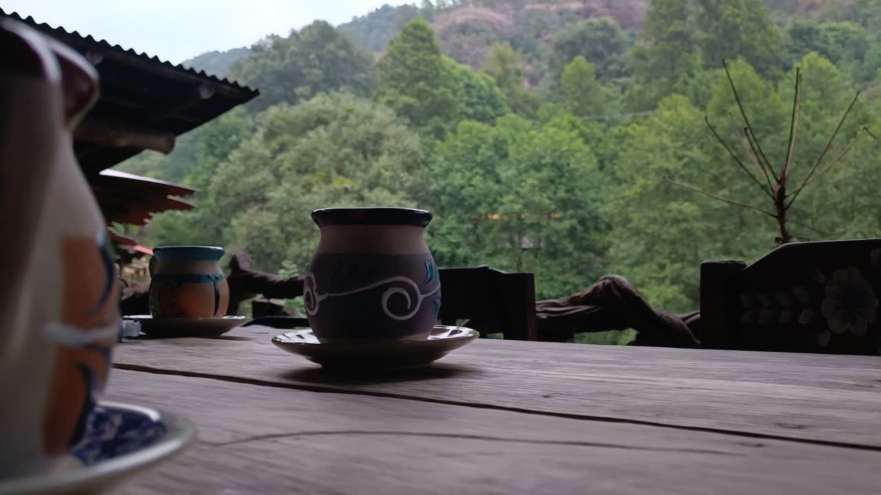 Ceramic mugs on rustic table with lush green forest view in tranquil outdoor setting