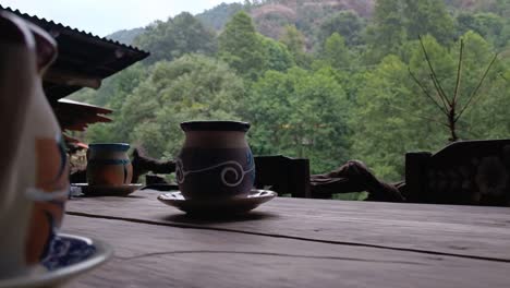 ceramic mugs on rustic table with lush green forest view in tranquil outdoor setting