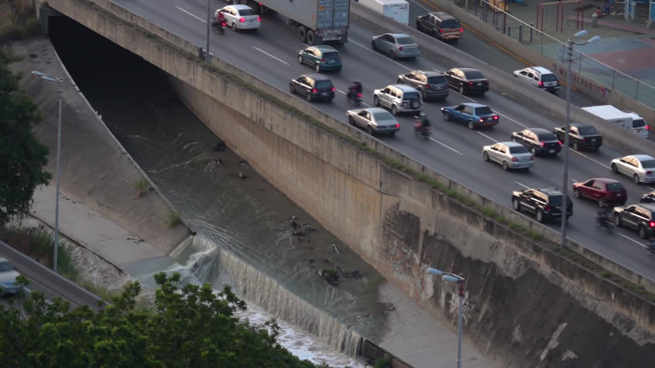 Valle-Coche highway and one of the black water exits that leads to the Guaire River, in the city of Caracas, Venezuela at dusk from a high angle.