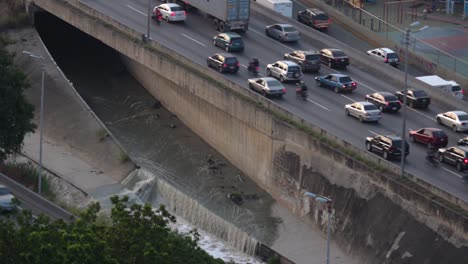 valle-coche highway and one of the black water exits that leads to the guaire river, in the city of caracas, venezuela at dusk from a high angle.