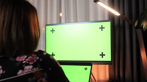 woman using computer with green screen at home. concentrated female professional analyzing market, researching information online in internet on computer at office home workplace
