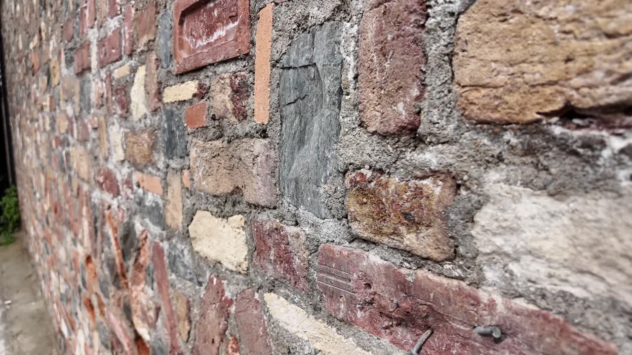 Panorâmica em close-up de uma antiga parede de tijolo e pedra desgastada.