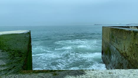 a stormy ocean slams against a concrete breakwater - pontão da barra do douro - molhe norte, porto, portugal