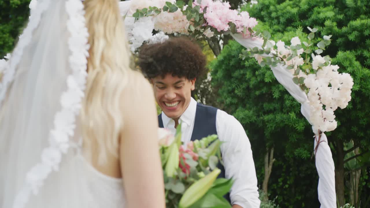 feliz pareja diversa en el jardín en un día soleado en la boda