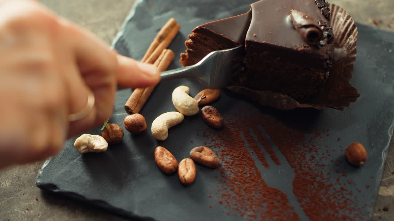 mano humana de primer plano cortando pastel de chocolate en cámara lenta.
