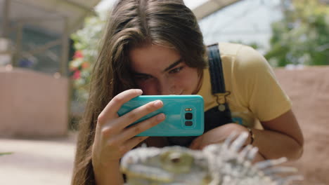 Chica-De-La-Naturaleza-Tomando-Una-Foto-De-Una-Iguana-Usando-Un-Teléfono-Inteligente-En-Un-Santuario-De-Vida-Silvestre-Aprendiendo-El-Hábitat-Natural-De-Los-Reptiles-Disfrutando-De-Una-Excursión-Al-Zoológico-Compartiendo-En-Las-Redes-Sociales-4k