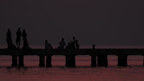 silhouettes on a pier at greek sunset