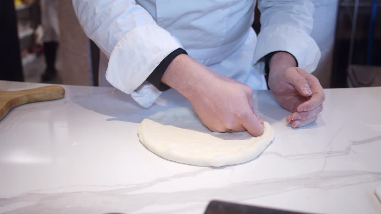 Chef che modella l'impasto della pizza sul tavolo della cucina del ristorante.