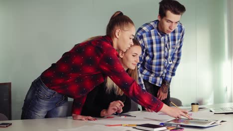 grupo de jóvenes en la reunión en un apartamento moderno. tres estudiantes trabajando en sus tareas sentados juntos en la mesa