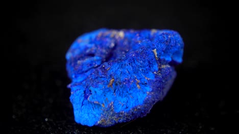 la rotación sin problemas de un mineral azul (azurita) frente a un fondo negro