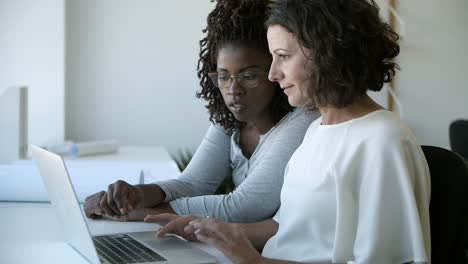 closeup shot of confident women talking while working with laptop