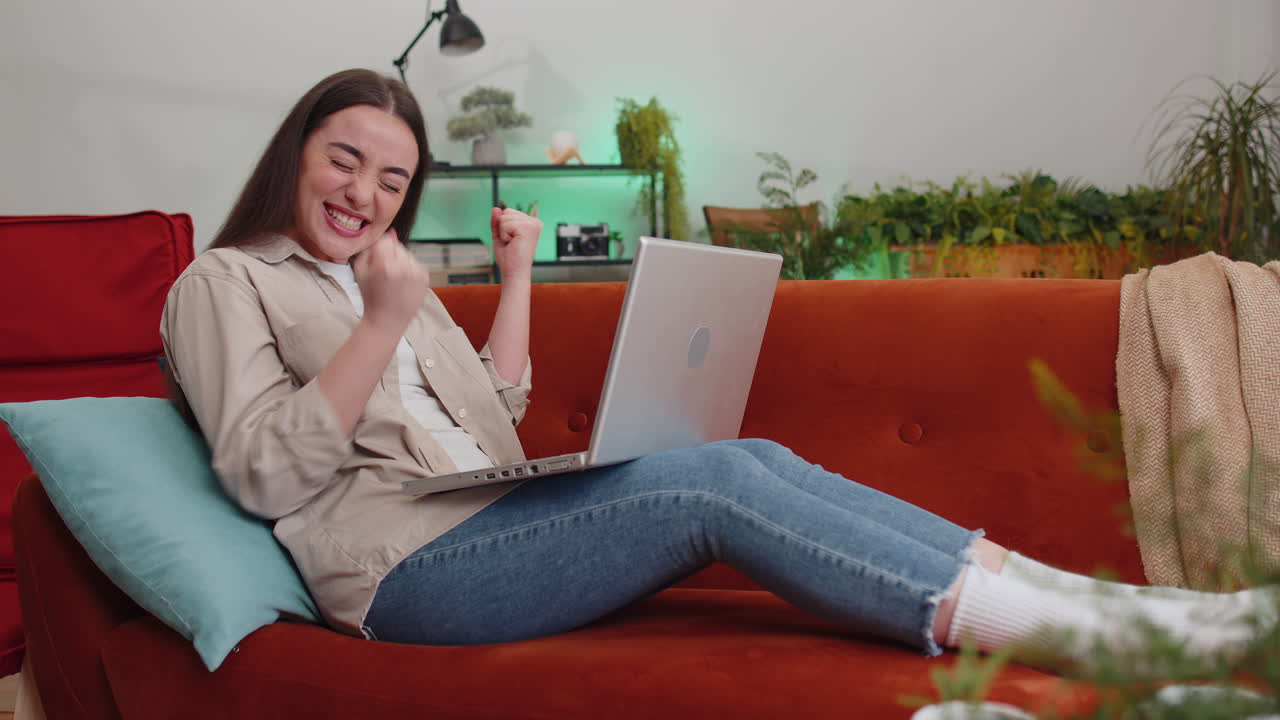 Amazed young woman use laptop computer receive good news message shocked by victory celebrate win
