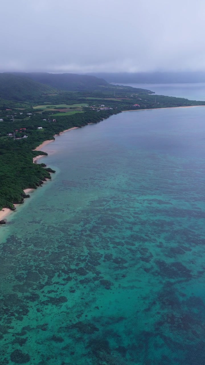 Volo aereo nuvoloso intorno alla spiaggia della penisola di Hirakubo verso il faro di Hirakubozaki con nuvole di pioggia e acqua blu scuro, Isola di Ishigaki, Okinawa, Giappone
