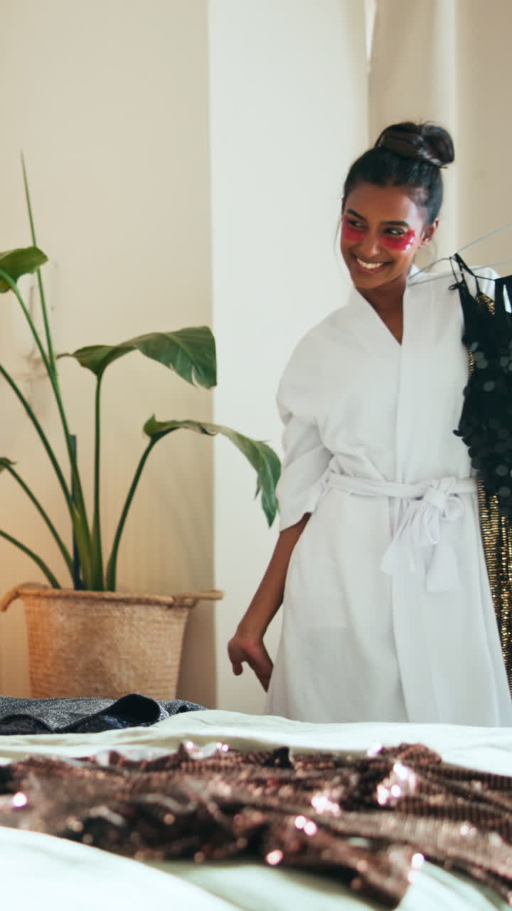 Happy Woman in Robe Choosing Sequin Dress for a Party