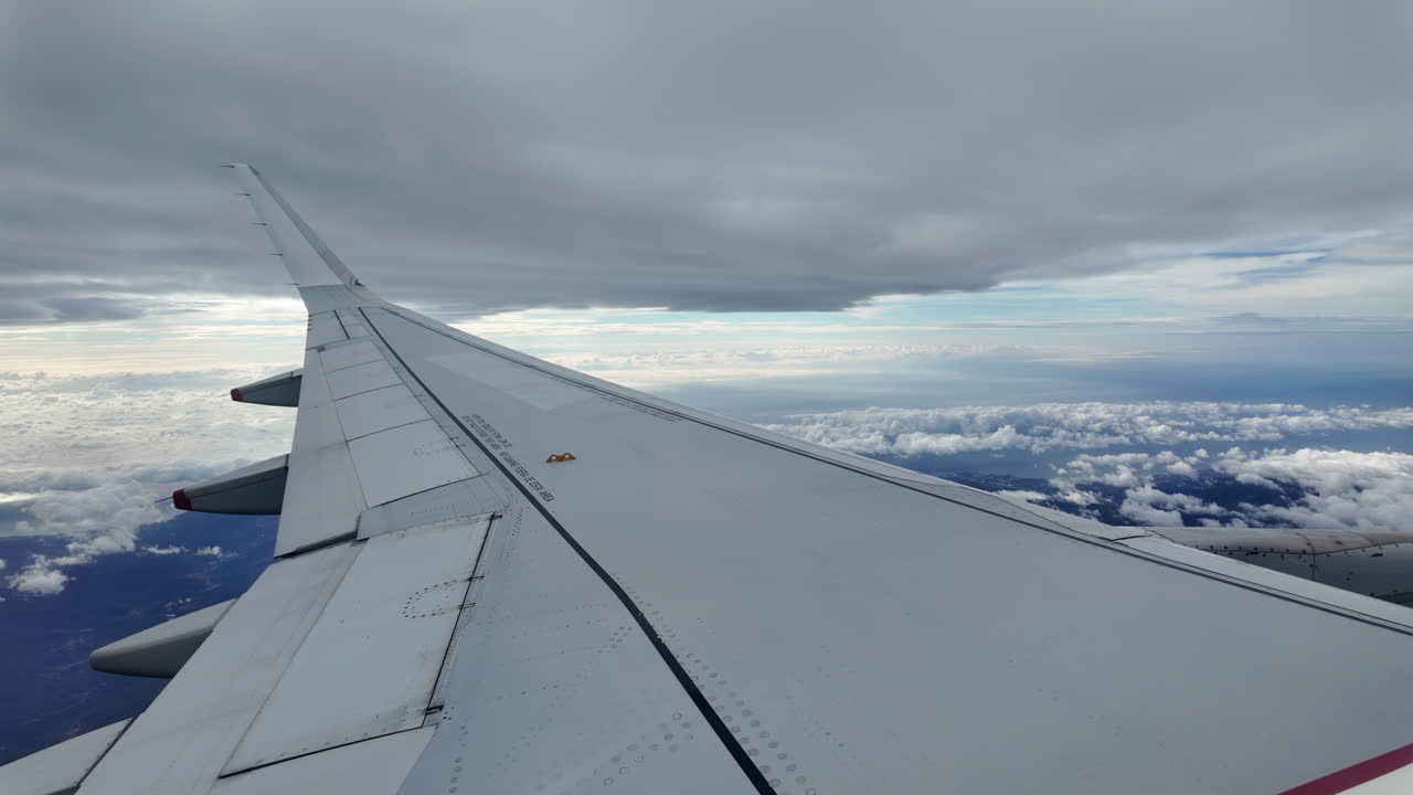 Aircraft wing gliding above layered clouds viewed from the window seat