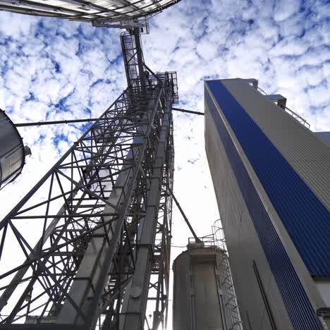 metal construction on a modern industrial plant. large grain elevators on beautiful sky background. view from below.