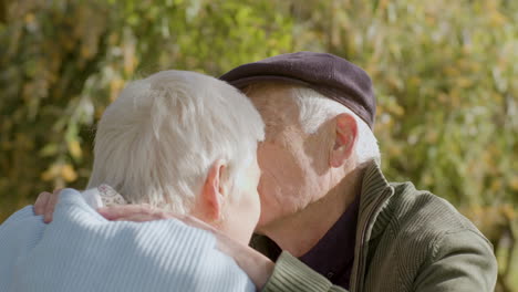 Romantisches-Seniorenpaar-Küsst-Und-Reibt-Nasen,-Während-Es-An-Einem-Sonnigen-Herbsttag-Zeit-Im-Park-Verbringt