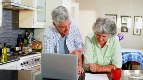 pareja de ancianos discutiendo la factura mientras usan una computadora portátil 4k