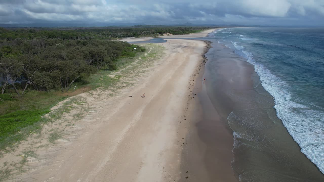 volando sobre la playa de arena, la playa de belongil y el arroyo en nsw, australia - disparo de avión no tripulado
