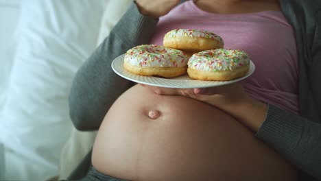 close up video of pregnant woman eating donuts.