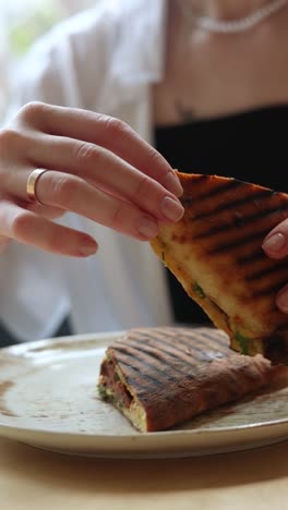 mujer comiendo un sándwich a la parrilla