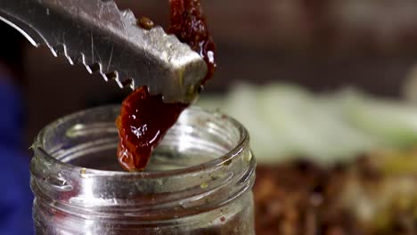 Close-up-of-sun-dried-tomatoe-being-taken-out-of-glass-jar