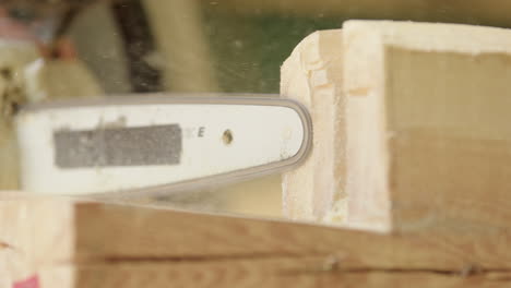 wood shavings and sawdust flying as chainsaw carves piece of timber