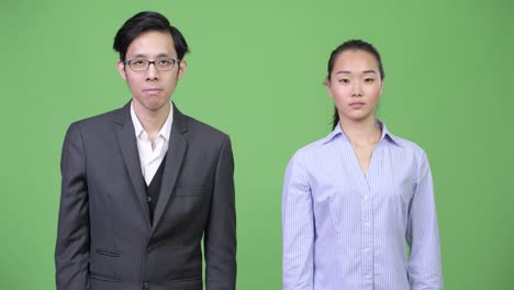 young asian business couple pointing at camera together