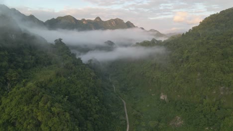 drone moves toward cloudy mountain with golden light on the peak and road under the cloud