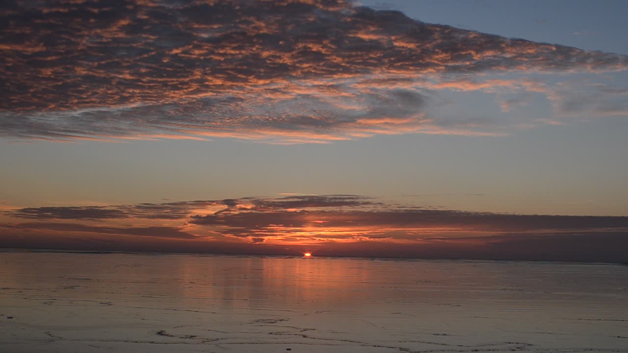 Solnedgang over det frysende hav. Nydannet is i bevægelse