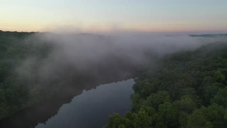 beautiful forest river with rising fog in early summer morning, aerial view